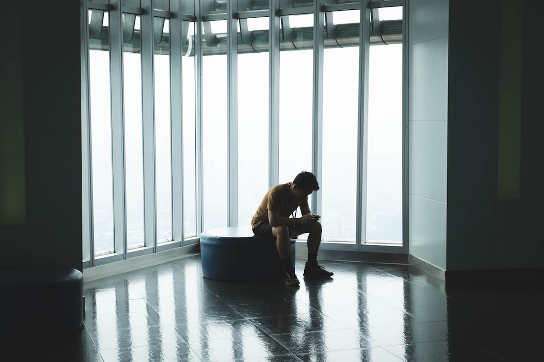 man sitting on ottoman chair near window