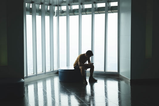 man sitting on ottoman chair near window