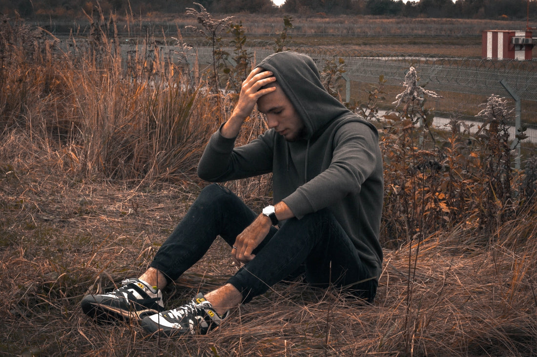 man in black jacket and black pants sitting on brown grass field during daytime