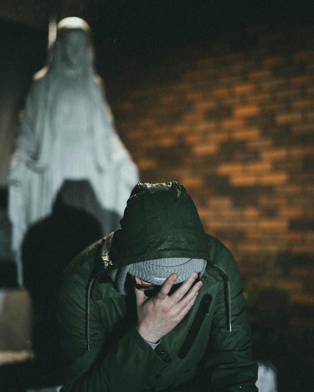 person in green jacket covering face with white textile
