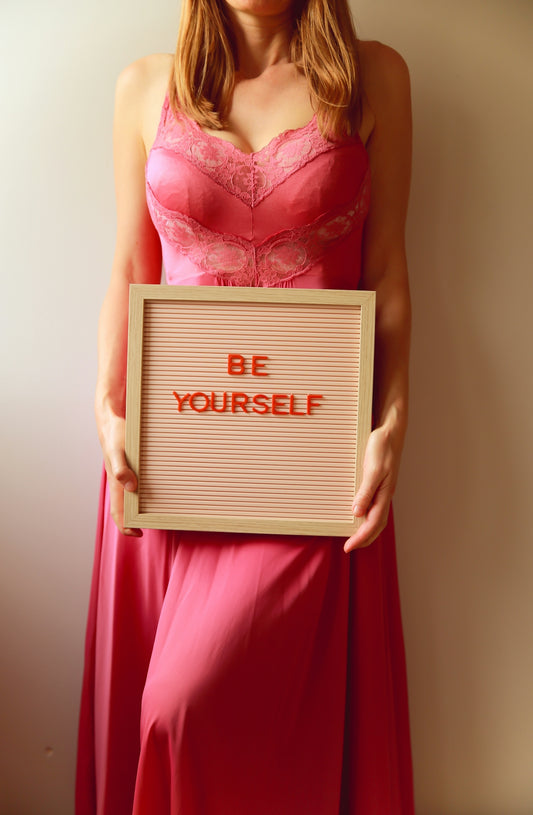 Woman holds a sign that reads, be yourself.