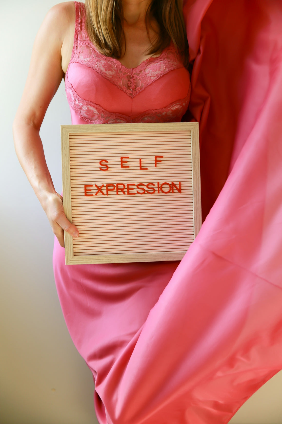Woman holding a sign that reads self expression.