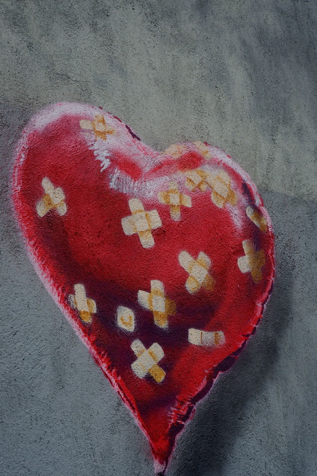 A red heart with many bandages on it