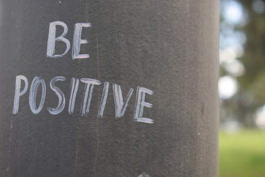 Be positive written on a dark pole.