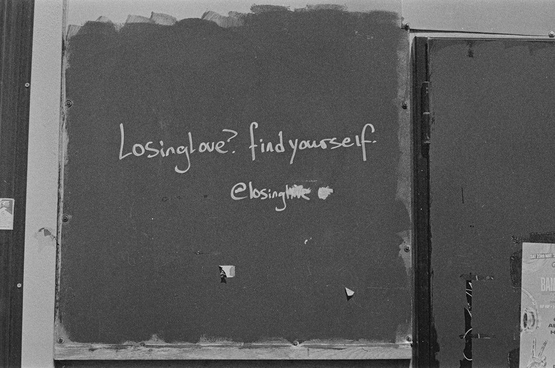 White text 'losing love? find yourself.' on a dark wall.